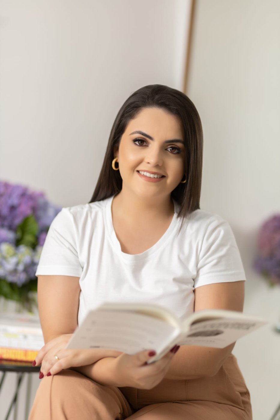 Luana segurando um livro aberto de Psicologia e sorrindo